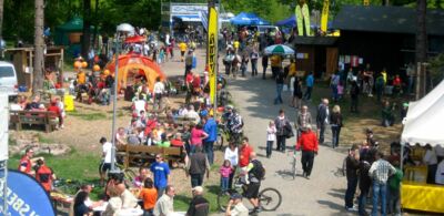 Zahlreiche Besucher und Fahrradfahrer tümmeln sich auf einem Markt in der freien Natur bei gutem Wetter