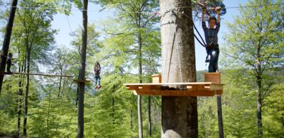 Spielende Kinder auf einer Ziplineplattform in den Baumwipfeln