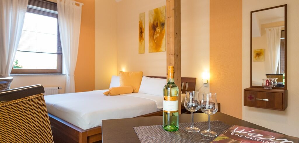 Weißweinflasche und Gläser in sauberem, hell gestaltetem Hotelzimmer